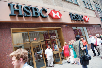 La gente camina por delante de una de las sucursales del Banco HSBC.