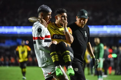 Un jugador de Sao Paulo lleva en sus brazos a Joao Rojas, tras su lesión en el partido ante Barcelona en Copa Libertadores.
