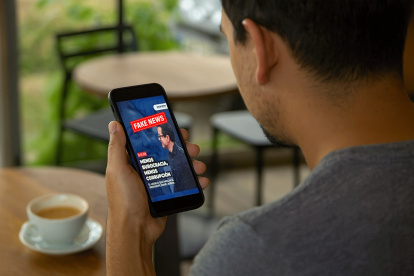 Una persona revisa en su celular una imagen que imita el diseño de Diario EXPRESO, parte de una campaña digital que busca posicionar mensajes políticos mediante montajes con apariencia de medios reales.