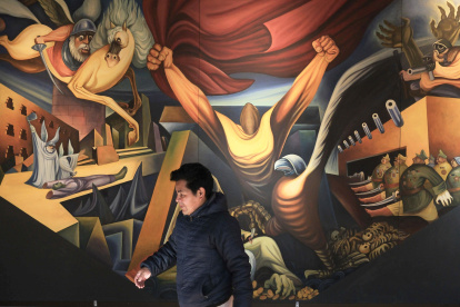 Una persona camina frente a un mural del pintor Miguel Alandia Pantoja en el Museo Nacional de Arte en La Paz (Bolivia).