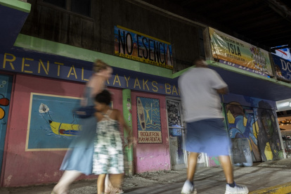 Personas pasan junto a un cartel en contra del proyecto Esencia en Cabo Rojo, Puerto Rico, el 15 de julio de 2025.