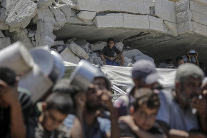 Un niño observa un grupo de palestinos agolpados con sus ollas esperando recibir alimentos de un comedor social en la Franja de Gaza.