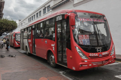 Ciudadanos esperan buses en una parada del centro de Cuenca, mientras varias rutas han sido suspendidas por falta de recursos.