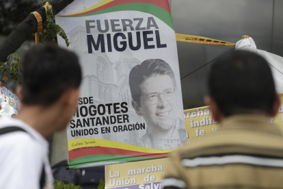 Fotografía de personas orando en un altar improvisado frente a la Fundación Santa Fe, lugar donde permanece hospitalizado el senador colombiano Miguel Uribe Turbay.