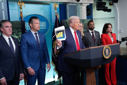 El presidente de Estados Unidos, Donald Trump, sostiene un documento junto al secretario de Defensa, Pete Hegseth (2-i), mientras se dirige a los medios de comunicación en Washington.