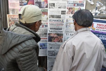 Dos personas leen periódicos con cobertura en portada de las elecciones presidenciales de Bolivia en un quiosco, en La Paz, el 18 de agosto de 2025.