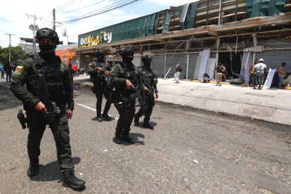 Integrantes de los Grupos Operativos Especiales de Seguridad (GOES) custodian locales comerciales afectados por la explosión, este viernes en Cali (Colombia).