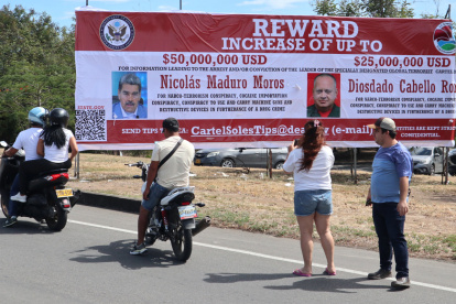 Personas observan una valla con la imagen del presidente de Venezuela, Nicolás Maduro, y su ministro de Interior, Diosdado Cabello, este sábado 23 de agosto en Villa del Rosario (Colombia).