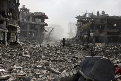 Un joven palestino permanece de pie en una calle sembrada de escombros tras una explosión en el barrio de Saftawi, al oeste de Jabalia, en el norte de la Franja de Gaza, el 25 de agosto de 2025.