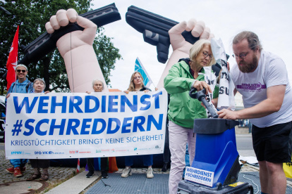 Manifestantes rompen simbólicamente un cartel en relación con la ley del servicio militar, el 27 de agosto de 2025, Alemania.