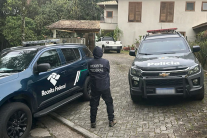 Oficial haciendo guardia afuera de una casa durante una operación dirigida a una red de lavado de dinero en Sao Paulo, Brasil, el 28 de agosto de 2025