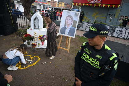Las mujeres depositan flores junto a un retrato del candidato presidencial asesinado Miguel Uribe en el lugar donde le dispararon el 7 de junio en el barrio Modelia de Bogotá