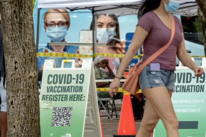 Personas caminan frente a un centro de vacunación contra la Covid-19.