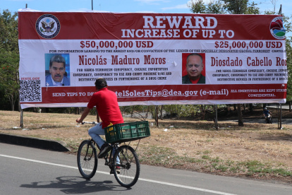Recompensa. Un hombre observa una valla con el anuncio de recompensa y la imagen del presidente de Venezuela, Nicolás Maduro, y de su ministro de Relaciones Interiores.
