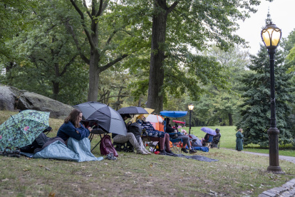 Espera. Personas haciendo fila para ver gratis obras de Shakespeare donde actúan reconocidos actores, en un escenario de Central Park. Permanecen así horas bajo lluvia y sol.