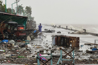 Un hombre se encuentra cerca de escombros en una carretera costera en medio de fuertes lluvias debido a los patrones climáticos del súper tifón Ragasa en la ciudad de Aparri, Filipinas.