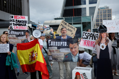 Los manifestantes sostienen una efigie de Begoña Gómez y una pancarta que dice "España corrupta" mientras la esposa del primer ministro español.