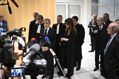 El ex presidente Nicolas Sarkozy habla con la prensa flanqueado por su esposa Carla Bruni (C-D) y el abogado francés Jean-Michel Darrois, en el tribunal del Tribunal de París, el 25 de septiembre de 2025.