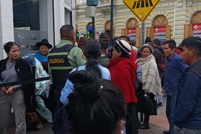 Ciudadanos esperan en el exterior de BanEcuador de Riobamba para ver si es beneficiario del Bono Raíces.