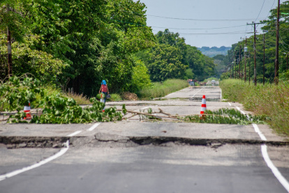 Una mujer camina junto a carretera dañada un día después de que un terremoto de magnitud 6,3 sacudiera la ciudad de Mene Grande en el estado Zulia, el 25 de septiembre de 2025.