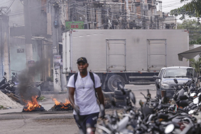 Una persona camina frente a barricadas en llamas durante un operativo policial este viernes, en Río de Janeiro (Brasil)