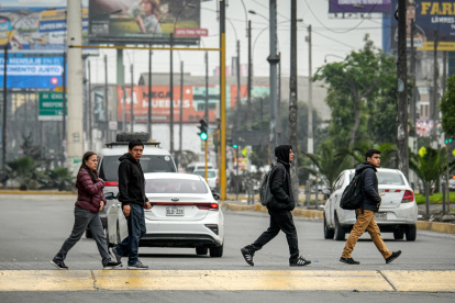Personas caminan por una calle durante una jornada de paro de transportadores en la ciudad de Lima (Perú).