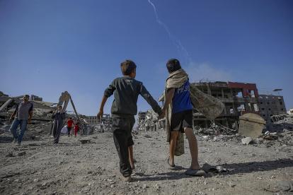 Palestinos caminan por una calle entre los escombros de edificios destruidos durante un alto el fuego entre Israel y Hamás en virtud de la primera fase del plan de paz de Gaza.