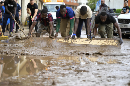 Varias personas trabajan en la limpieza de las calles durante la mañana de este lunes cuando la dana que desde ayer azota el sur de Cataluña.