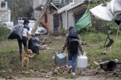 Personas caminan con sus pertenencias en una zona afectada por las fuertes lluvias el 12 de octubre de 2025, en Huauchinango (México).