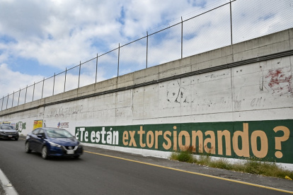 Los conductores pasan junto a un grafiti del gobierno que insta a la gente a denunciar los casos de extorsión en Ecatepec, México, el 2 de octubre de 2025.