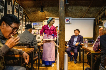 Son Yun-kyung (de pie) sirve dumplings mandu al estilo norcoreano a personas mayores y refugiados norcoreanos en la isla Gyodong, el 7 de octubre de 2025.