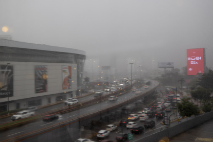 Vehículos transitan por la avenida John F. Kennedy bajo la lluvia provocada por el huracán Melissa este lunes, en República Dominicana.