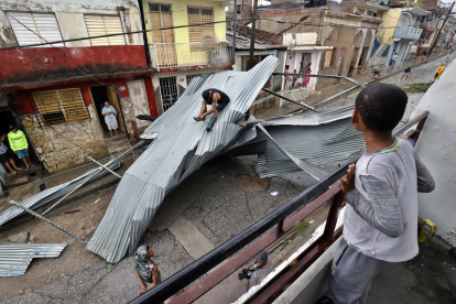 Personas recogen escombros en una calle afectada por el paso del huracán Melissa este miércoles, en Santiago de Cuba (Cuba).