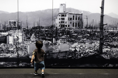 Un niño camina hacia una gran foto de la ciudad de Hiroshima devastada tras la explosión nuclear. (Japón, Estados Unidos)