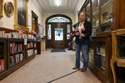 Sylvie Boudreau, presidenta de la junta directiva de la biblioteca transfronteriza Haskell, posa para una fotografía de pie sobre el marcador negro que indica los lados de EE. UU. (izq.) y Canadá, dentro de la biblioteca.