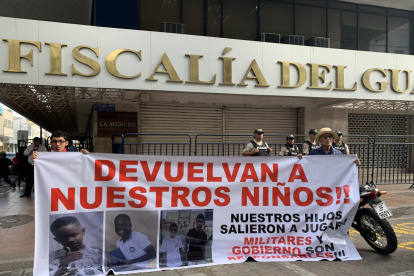 Archivo del 23 de diciembre de 2024 que muestra dos personas sosteniendo un cartel en los exteriores de la Fiscalía Provincial del Guayas.