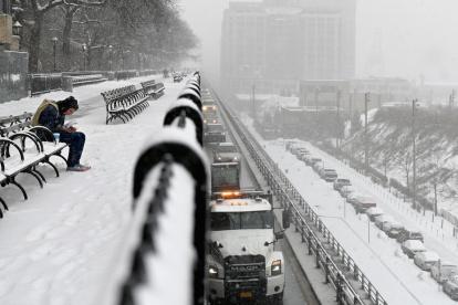 Un hombre se sienta en un banco durante una nevada en Nueva York, en febrero.
