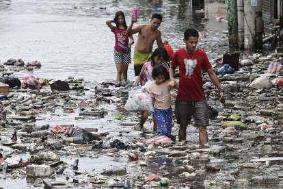 Un grupo de niños camina por las calles inundadas de Manila, Filipinas este lunes tras el paso del tifón Fung-Wong.