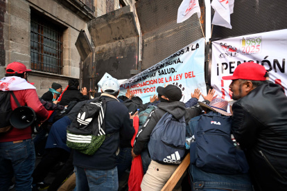 Integrantes de la Coordinadora Nacional de Trabajadores de la Educación (CNTE), se manifiestan afuera del Palacio Nacional de la Ciudad de México (México).