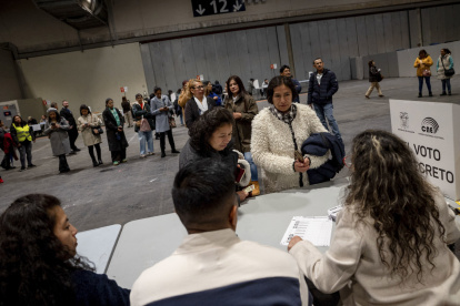 Votantes ecuatorianos hacen cola para ejercer su derecho al voto en el centro de votación instalado en el centro de convenciones IFEMA de Madrid, este domingo.