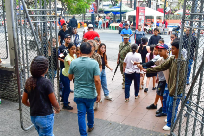 Varias personas, entre niños, tratan de convencer a los electores a que plastiquen con ellos el certificado de votación.