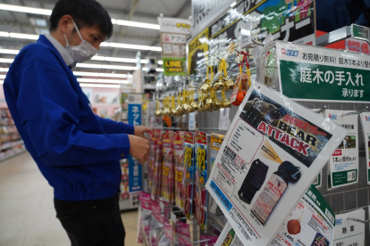Un empleado clasifica campanillas junto a un anuncio de spray para osos en una tienda de Hanamaki, prefectura de Iwate, el 24 de octubre de 2025.