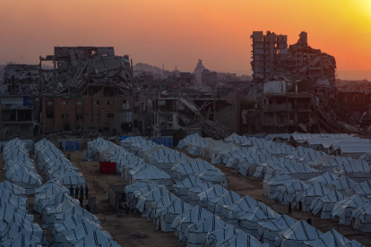 El sol se pone tras las ruinas de edificios destruidos y filas de tiendas de campaña de familias desplazadas en la Franja de Gaza, el 18 de noviembre de 2025.
