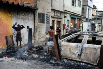 Un integrante de la Policía de Río de Janeiro custodia a dos personas durante un operativo , en Río de Janeiro (Brasil).
