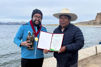 El ultranadador ecuatoriano Juan Pablo Flores (i) recibió un certificado por haber completado los 21 kilómetros entre la ruta Gruta de Lourdes (Bolivia) - Pomata (Perú).