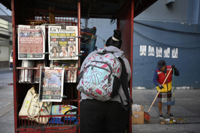 Una mujer se encuentra frente a un quiosco que muestra las portadas de los periódicos en Tegucigalpa, el 1 de diciembre de 2025, el día después de las elecciones nacionales.
