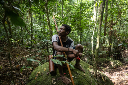 Un hombre maniq descansando en una roca y comiendo fruta silvestre, durante una expedición de caza en Phatthalung, en el sur de Tailandia.