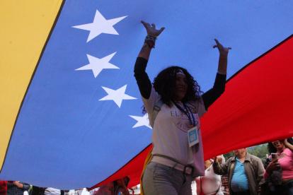 Una mujer camina debajo de una bandera durante la marcha "por la paz y la libertad" en Venezuela.