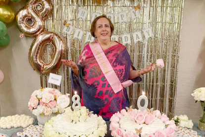 La cumpleañera junto a la mesa de dulces.