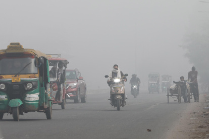 Vehículos transitan por calles en Nueva Delhi con poca visibilidad debido a la contaminación del aire en India.